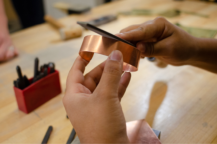 Individual using a metal file on copper band.