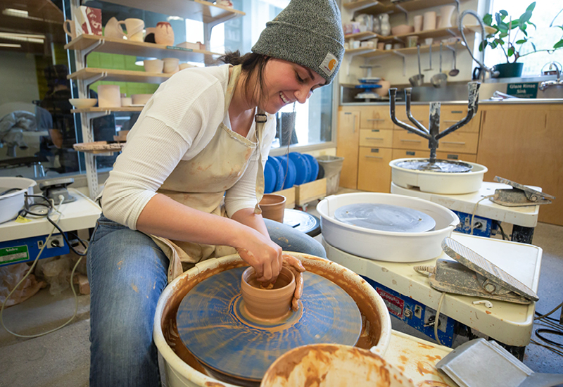 Craft Center member using a pottery wheel to make clay planter.