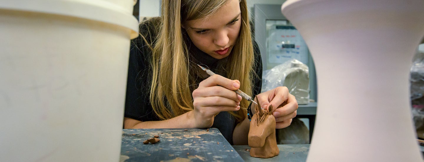 Craft Center member modeling clay unicorn.