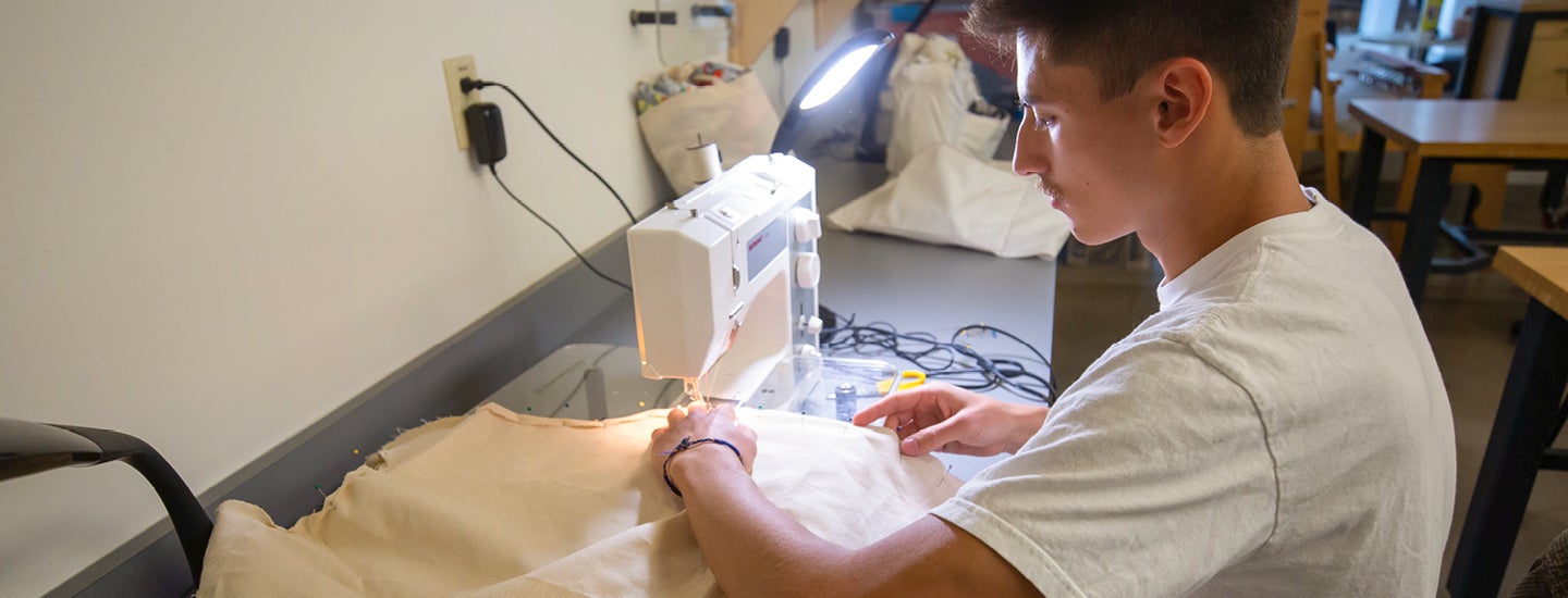 Craft Center member using sewing machine on fabric.