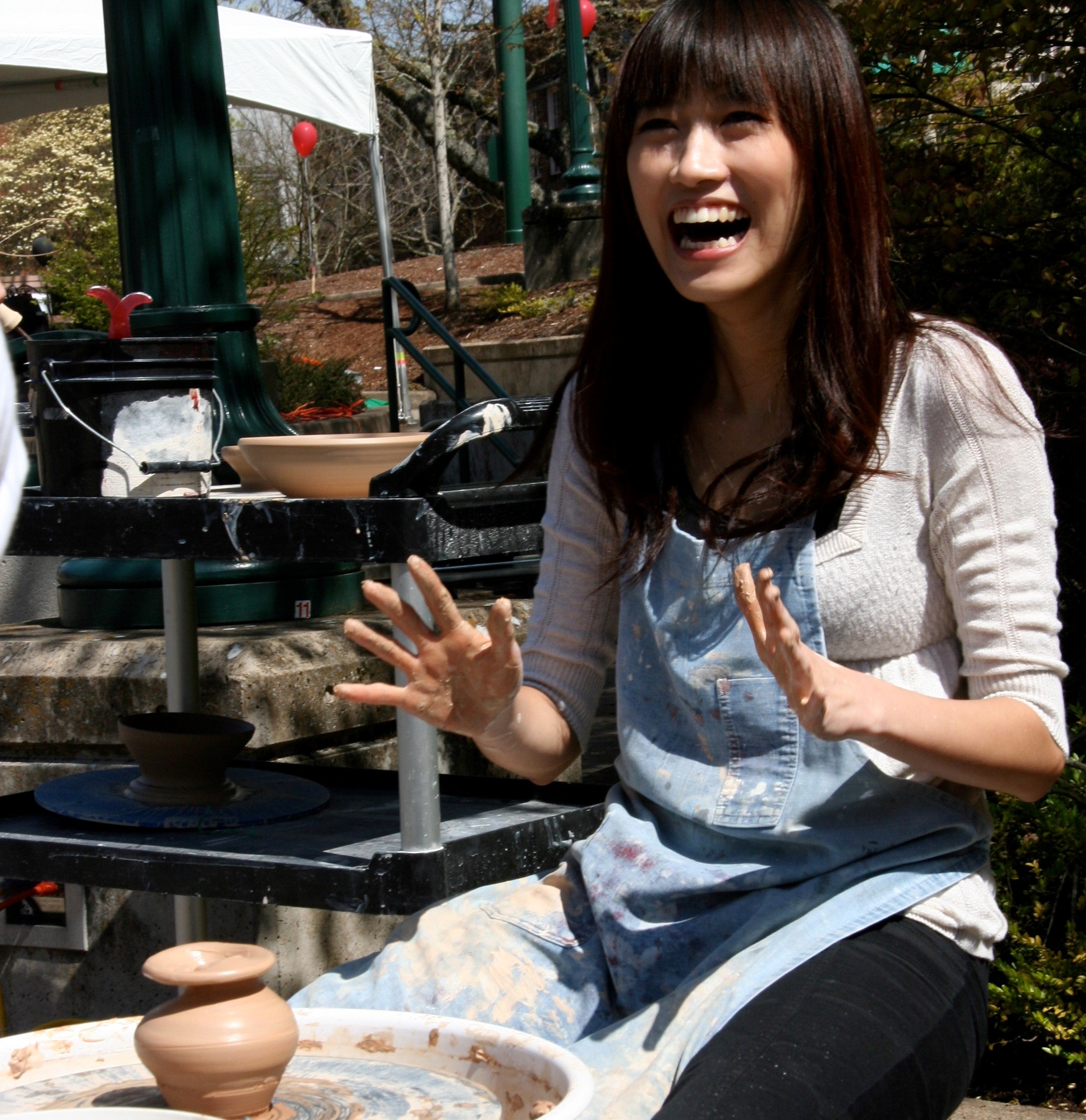 Novice ceramicist wearing an apron excited at the wheel thrown pot they have made