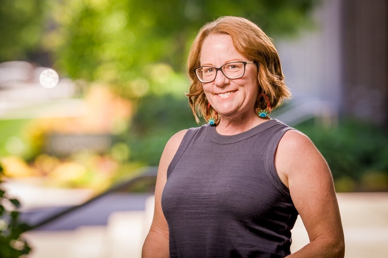 Woman with auburn hair in a dark gray tanktop