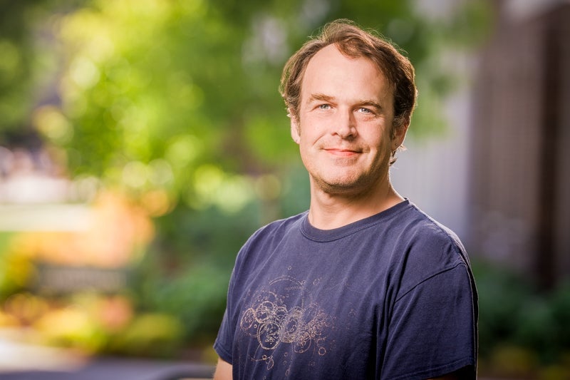 Man with short brown hair in a dark blue T-shirt