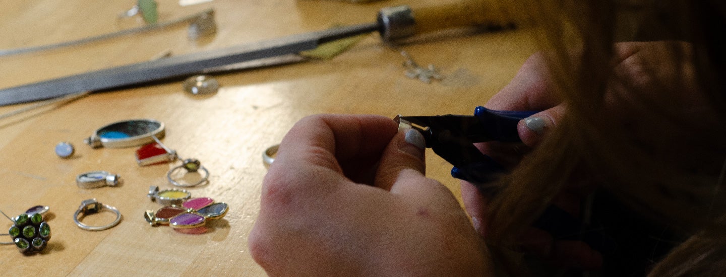 Student using metal cutter to work on metal ring.
